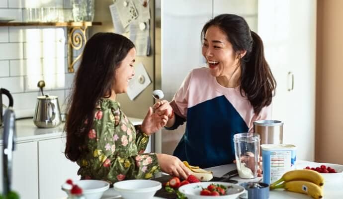 Donna e bambino che ridono mentre preparano il cibo