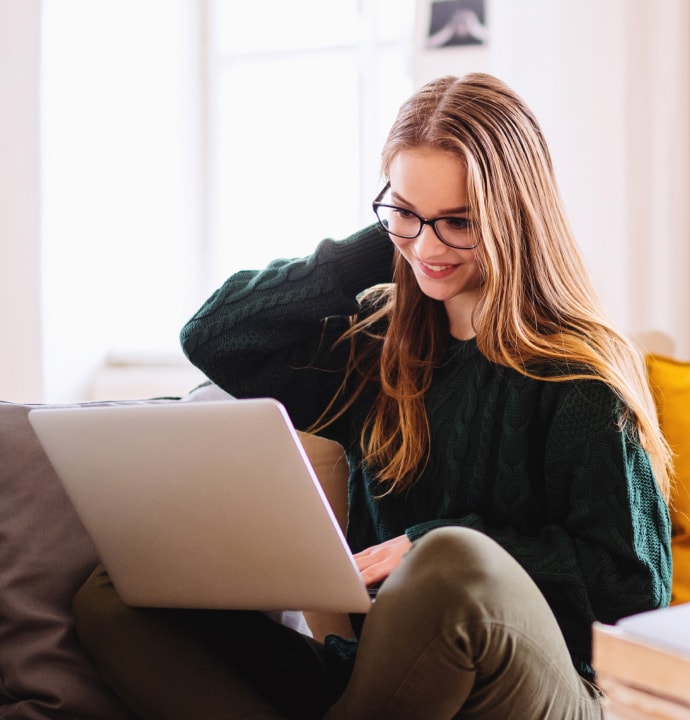 Ragazza sul divano che utilizza un computer portatile su cui si sta avviando Norton 360 Standard.