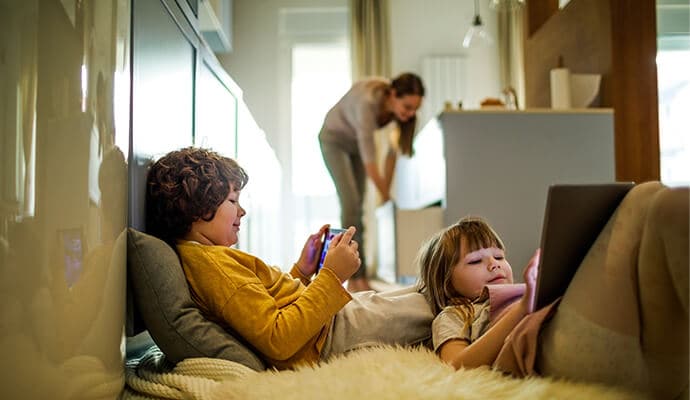 Bambini che usano tablet e madre sullo sfondo